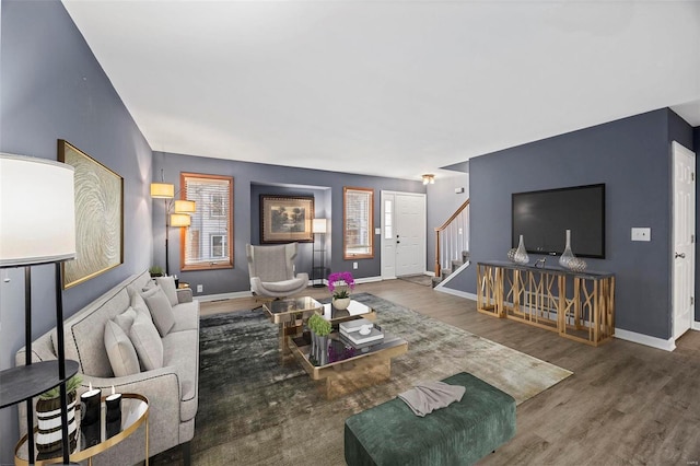 living area with stairway, wood finished floors, and baseboards