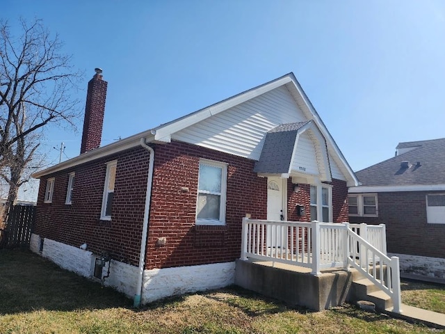 bungalow-style house with brick siding and a chimney