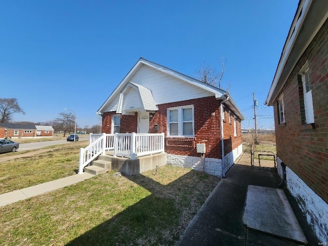 bungalow-style house with brick siding, covered porch, and a front yard