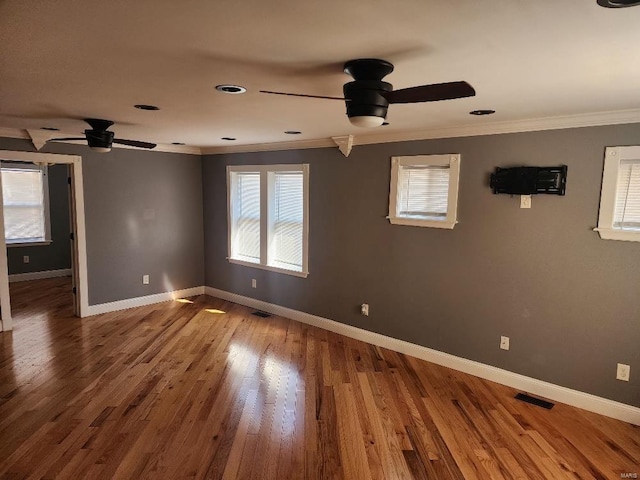 spare room featuring visible vents, crown molding, baseboards, and wood finished floors