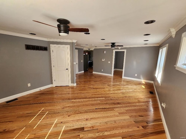 empty room featuring visible vents, light wood-type flooring, and ornamental molding