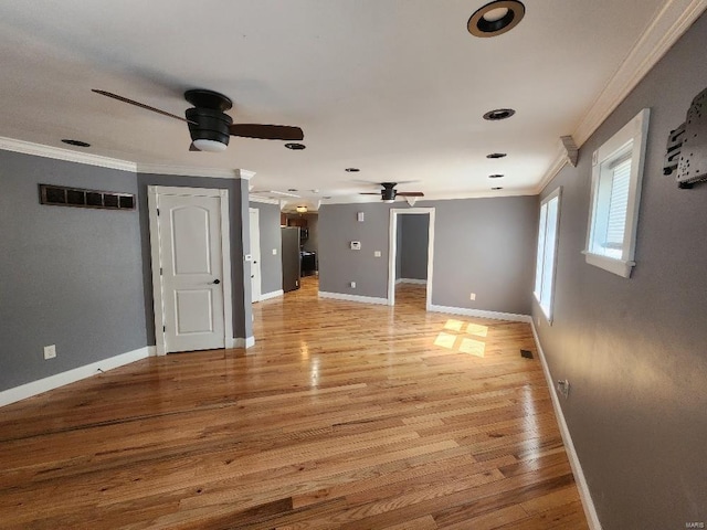 spare room with visible vents, baseboards, ceiling fan, light wood-type flooring, and ornamental molding