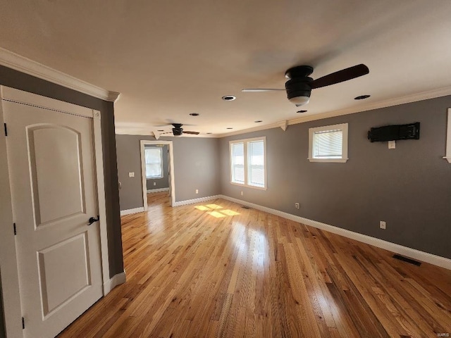 empty room with light wood finished floors, visible vents, baseboards, ornamental molding, and a ceiling fan