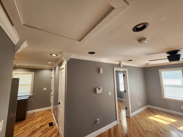 hallway featuring visible vents, light wood-type flooring, baseboards, and ornamental molding