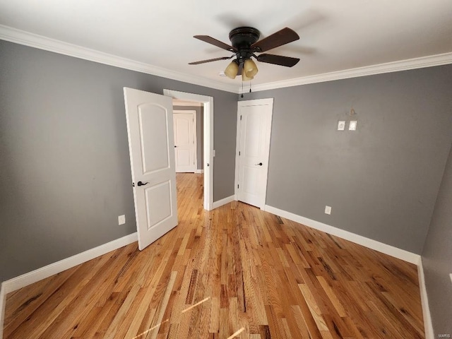 unfurnished room with ceiling fan, light wood-style floors, baseboards, and ornamental molding