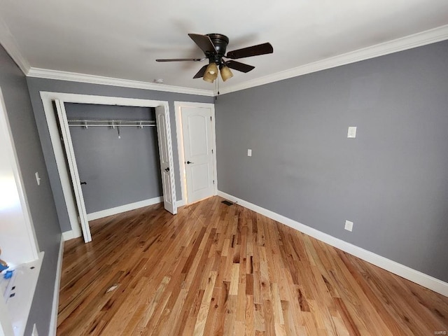 unfurnished bedroom with crown molding, baseboards, light wood-type flooring, and a closet