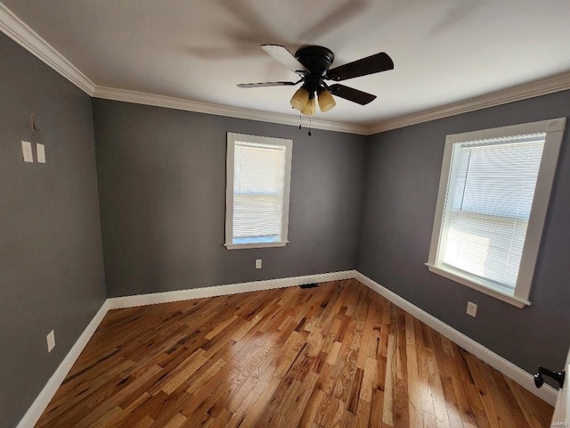 empty room featuring visible vents, baseboards, ornamental molding, light wood-style floors, and a ceiling fan