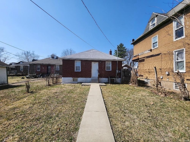 bungalow-style house featuring brick siding, a front lawn, fence, cooling unit, and a chimney