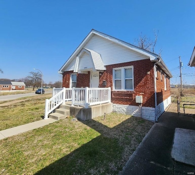 view of front of home with brick siding, a porch, and a front lawn