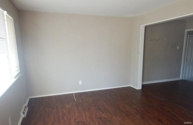 spare room featuring visible vents, baseboards, and wood finished floors