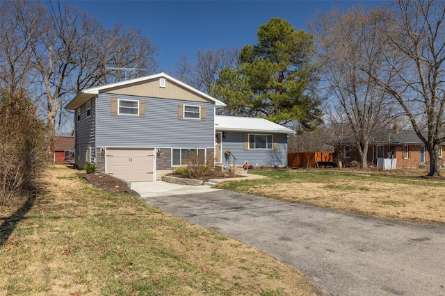 split level home with a front yard, a garage, and driveway