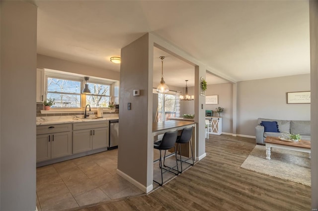 kitchen featuring a notable chandelier, a sink, open floor plan, wood finished floors, and dishwasher