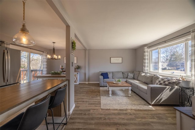 living area with dark wood finished floors, plenty of natural light, baseboards, and a chandelier