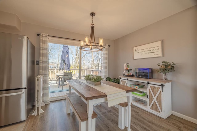 dining space with baseboards, an inviting chandelier, and wood finished floors