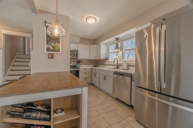 kitchen featuring light tile patterned floors, a sink, stainless steel appliances, tasteful backsplash, and butcher block counters