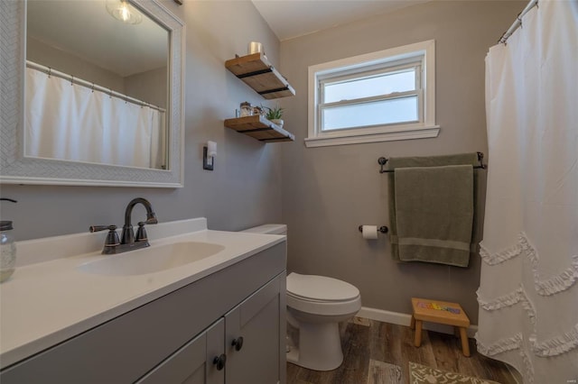 bathroom featuring vanity, toilet, wood finished floors, and baseboards