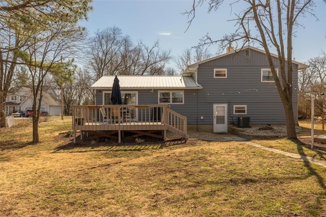 rear view of house featuring a deck, central air condition unit, a yard, and metal roof