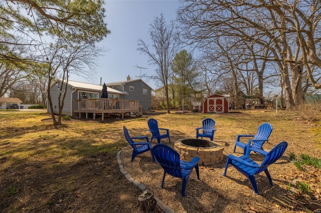 view of yard with an outdoor structure, a deck, a shed, and an outdoor fire pit