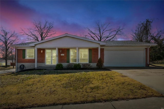 ranch-style house with brick siding, a yard, driveway, and a garage