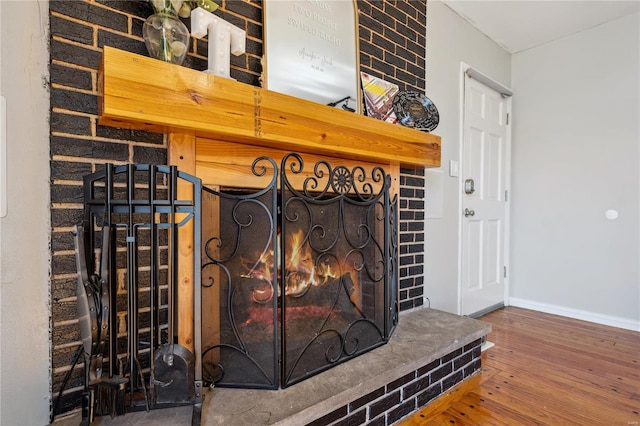 details with a brick fireplace, baseboards, and wood finished floors