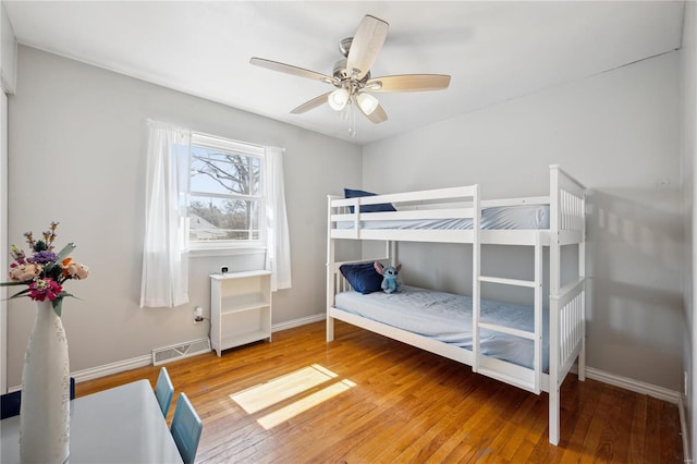 bedroom featuring visible vents, a ceiling fan, baseboards, and hardwood / wood-style flooring