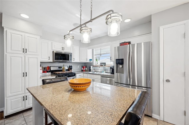 kitchen with a sink, a kitchen breakfast bar, appliances with stainless steel finishes, and white cabinetry