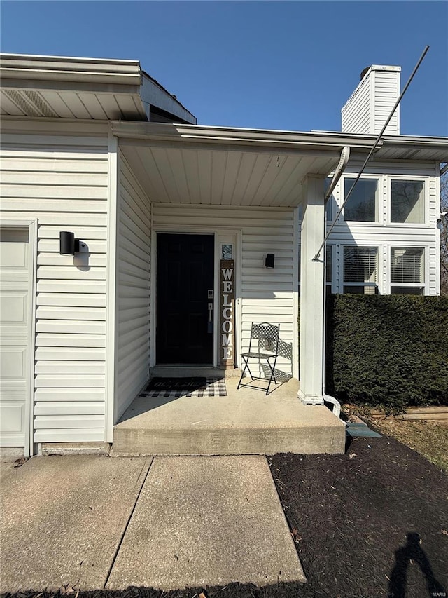 entrance to property featuring a chimney and an attached garage