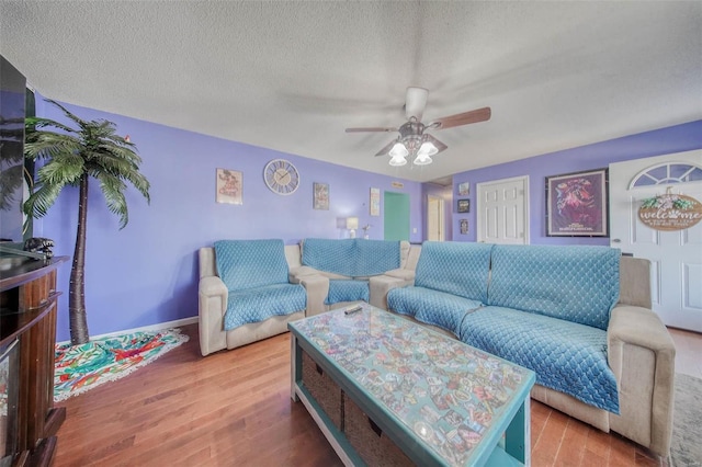 living room with baseboards, a textured ceiling, ceiling fan, and wood finished floors