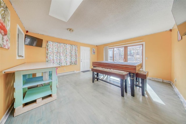 dining room featuring a baseboard heating unit, baseboards, a textured ceiling, and wood finished floors