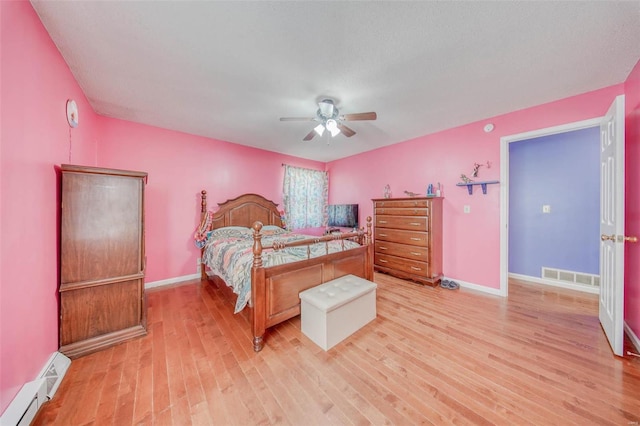 bedroom featuring baseboards, visible vents, baseboard heating, and light wood-style floors