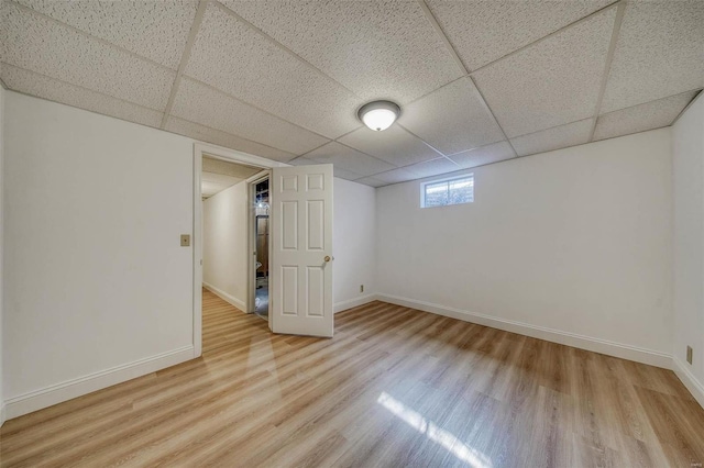 basement with a paneled ceiling, baseboards, and wood finished floors