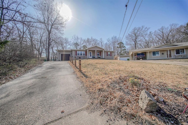 single story home with aphalt driveway, an attached garage, covered porch, and a front yard