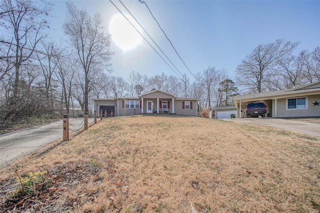 ranch-style house with an attached carport, aphalt driveway, a garage, and a front yard