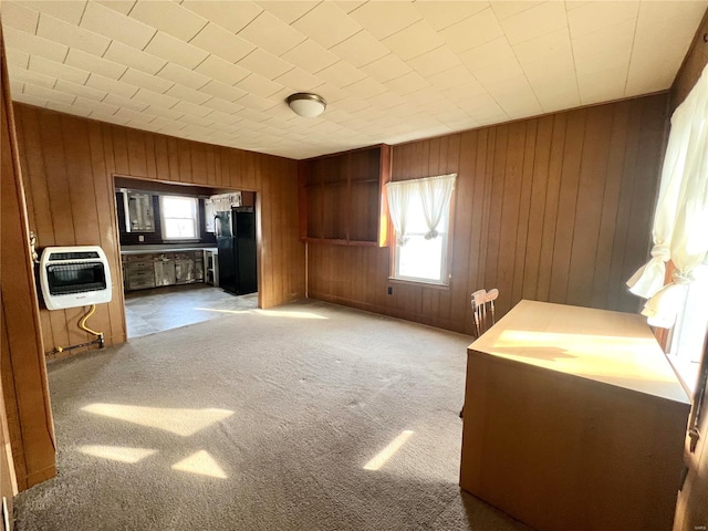 kitchen with heating unit, carpet flooring, wood walls, and freestanding refrigerator