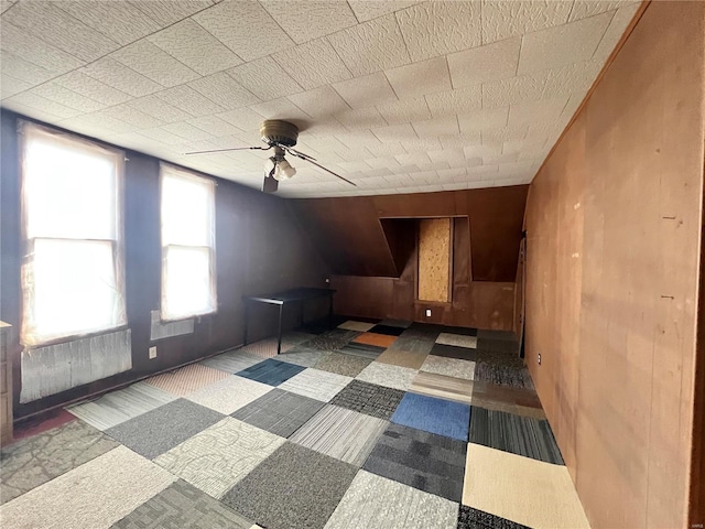 unfurnished room with wooden walls and a ceiling fan