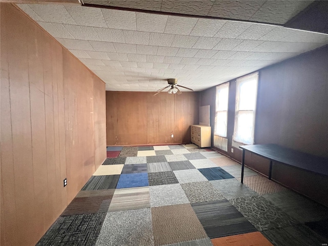 empty room featuring ceiling fan and wood walls