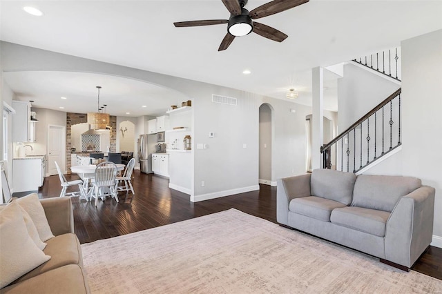 living room featuring visible vents, dark wood finished floors, and stairs