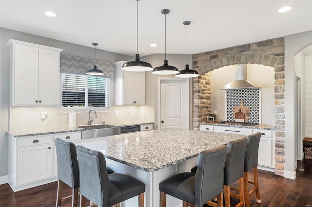 kitchen with tasteful backsplash, dark wood finished floors, wall chimney exhaust hood, and a sink