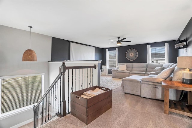 carpeted living area featuring baseboards and a ceiling fan