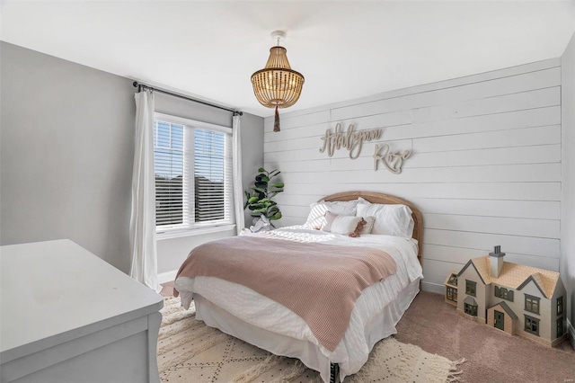 bedroom with light colored carpet, baseboards, and wood walls