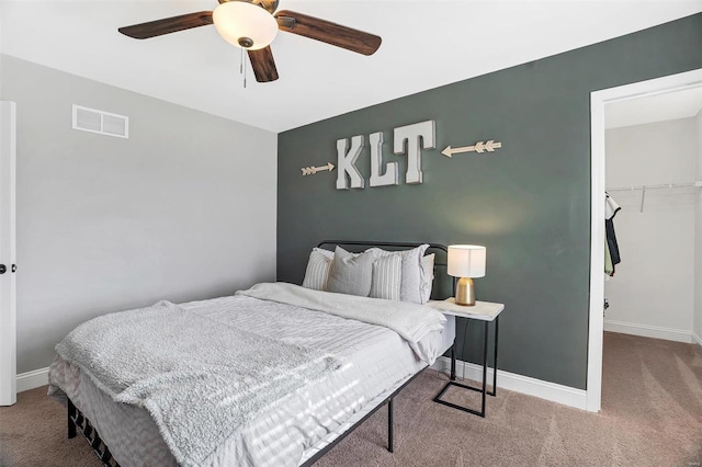 carpeted bedroom with a spacious closet, visible vents, baseboards, a closet, and a ceiling fan