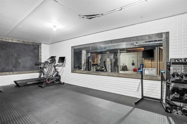 exercise room featuring carpet flooring and brick wall