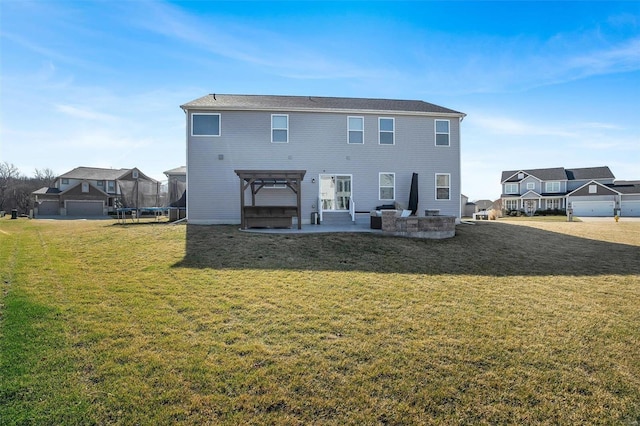 rear view of house featuring a trampoline, a patio area, and a lawn