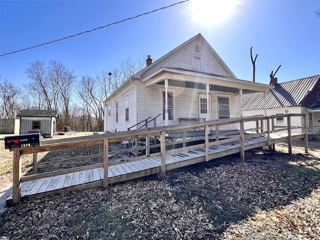 exterior space featuring a storage unit, an outbuilding, a wooden deck, and a chimney