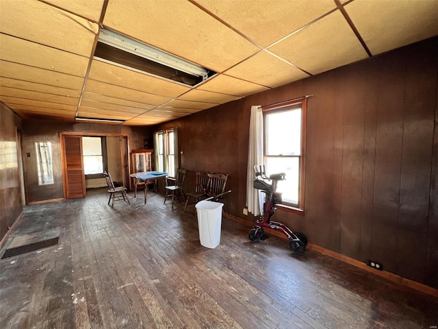 misc room with a drop ceiling, baseboards, and wood-type flooring