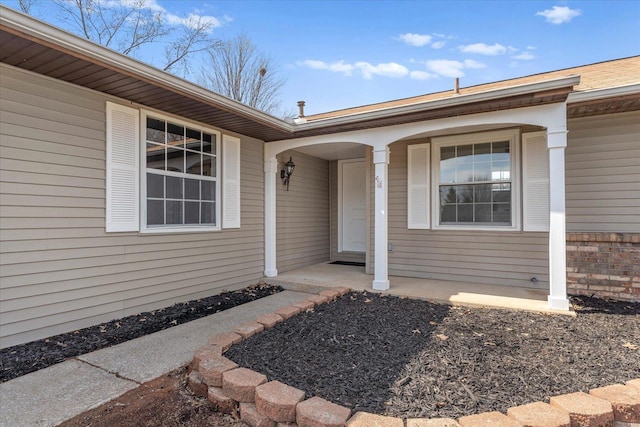 entrance to property featuring brick siding and covered porch