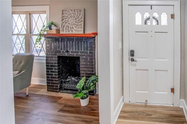 entryway with baseboards, wood finished floors, and a fireplace