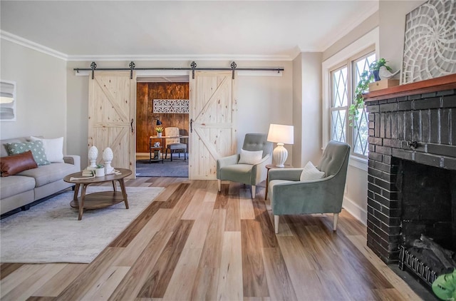 living room with a fireplace, a barn door, wood finished floors, and crown molding