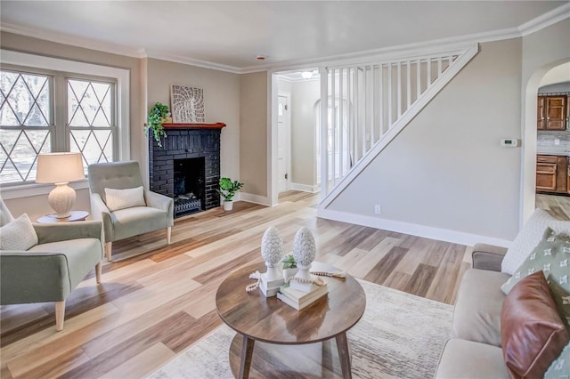 living area with stairs, arched walkways, light wood-style flooring, and crown molding