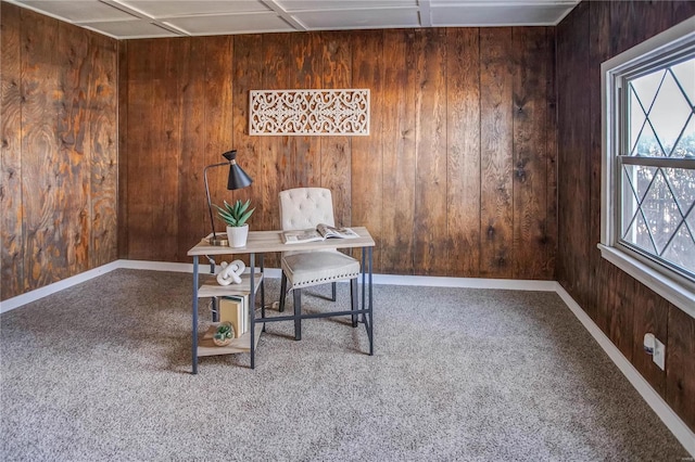 carpeted home office featuring wooden walls and baseboards